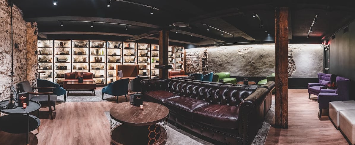 Intimate lounge interior featuring exposed stone walls, wooden beams, and curated bookshelves.