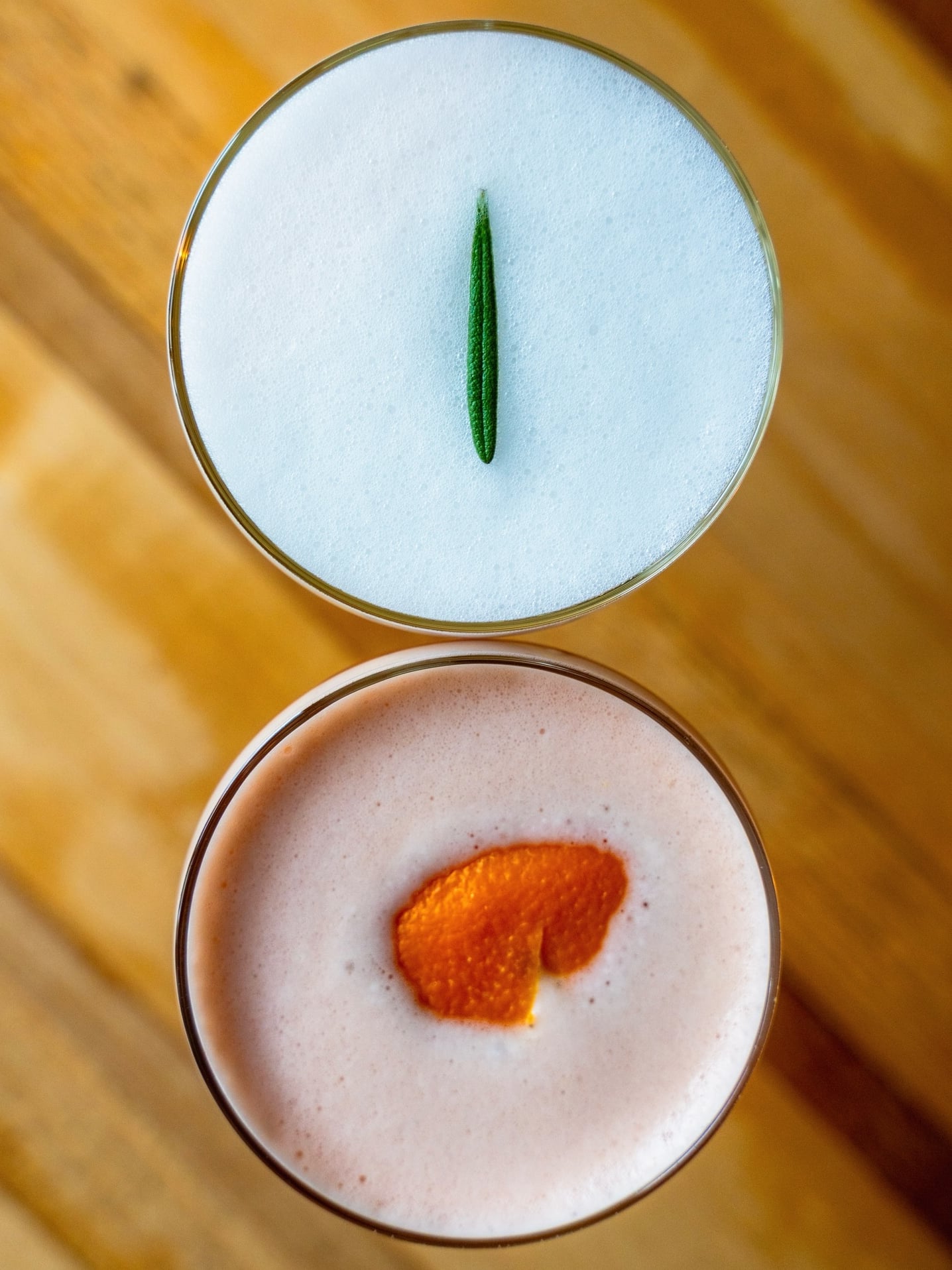 Signature cocktails with garnishes served on wooden tabletop.