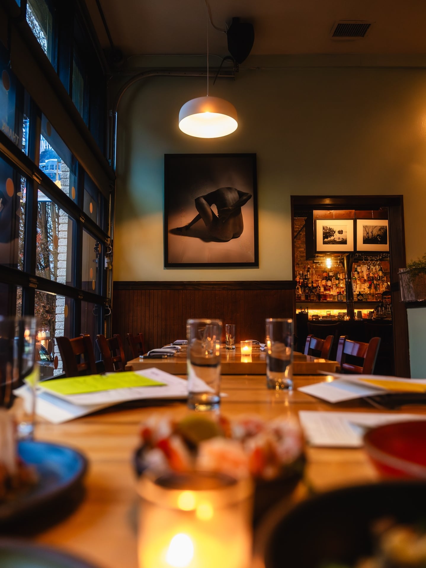 Warm interior ambiance featuring wooden tables and a view of the backlit bar.