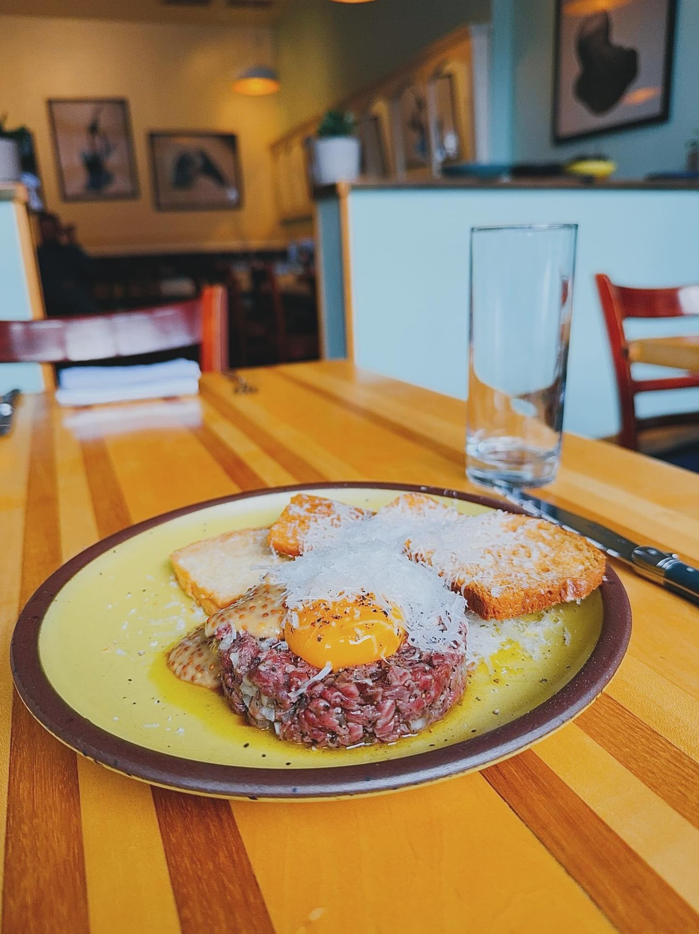 Steak tartare with toasted bread served on a striped wooden table.