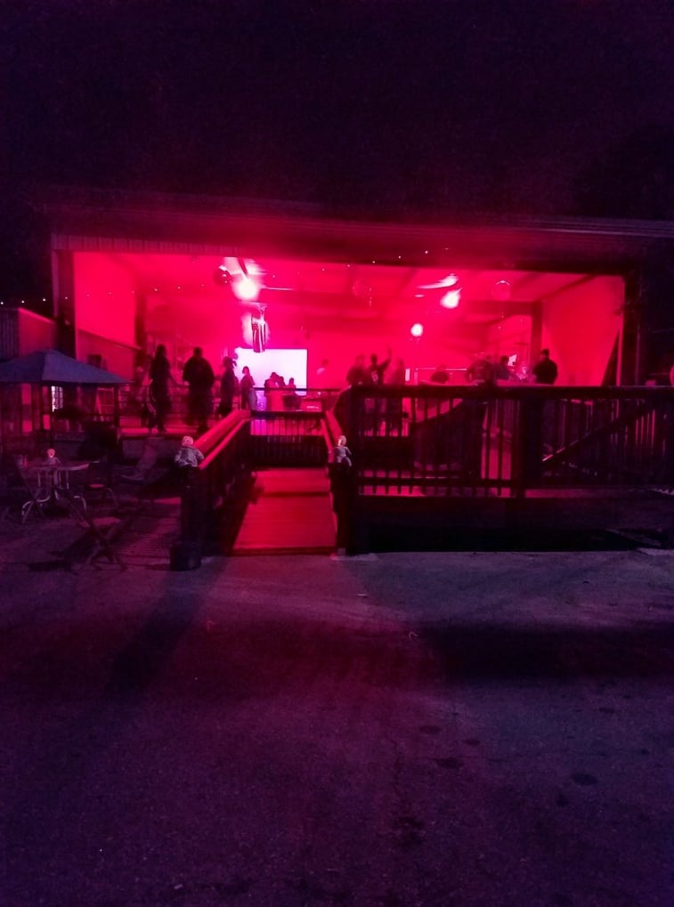 Covered outdoor stage entrance glowing red at night, with the patio and seating area beyond