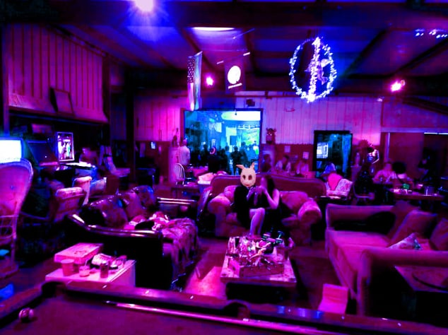 Eclectic lounge interior with vintage couches, arcade games, and colorful purple lighting