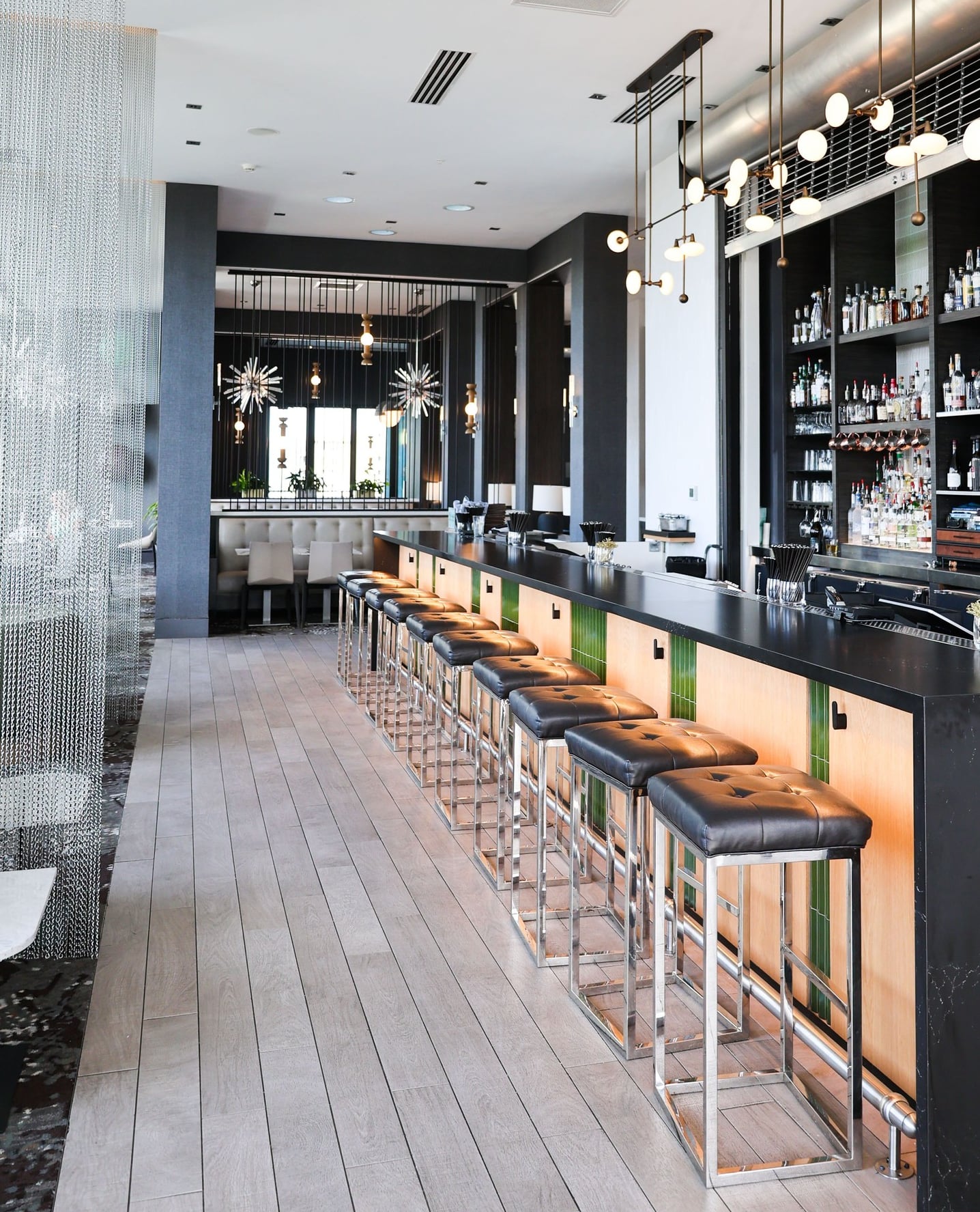 Contemporary bar with a fully stocked backbar and warm pendant lighting