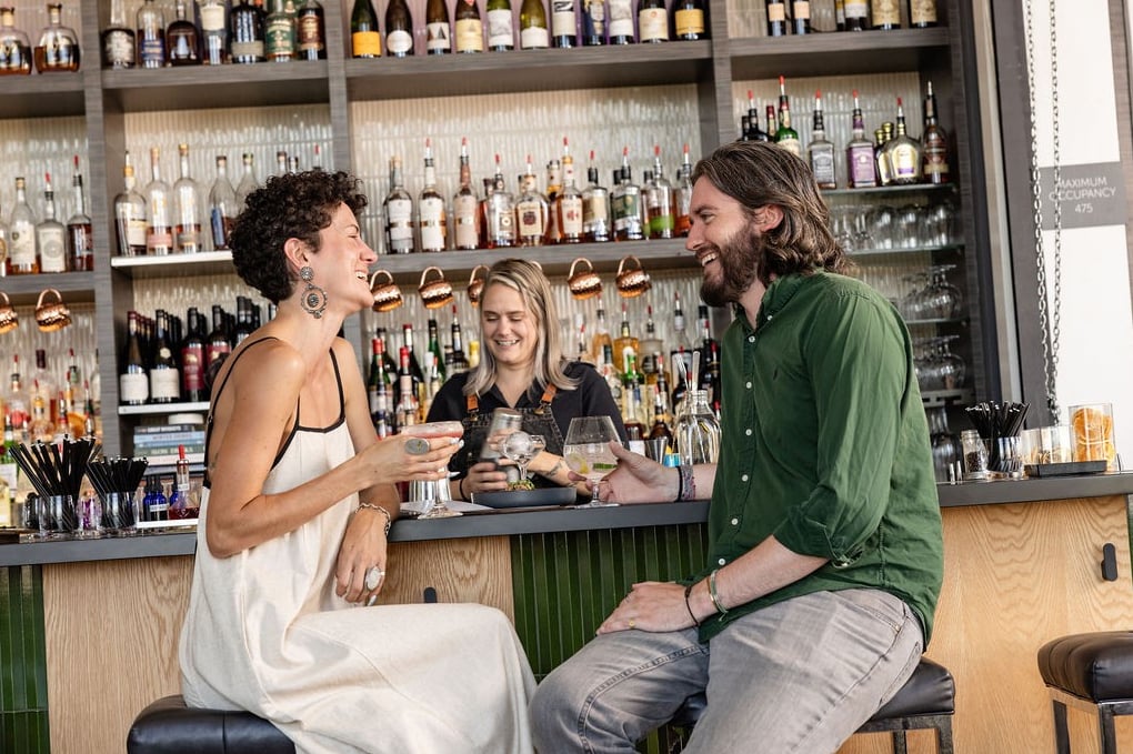 Bartender chatting with guests at the bar, backbar in view