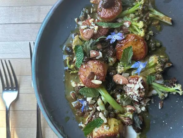 Seared scallops with charred broccolini, toasted almonds, and edible flowers