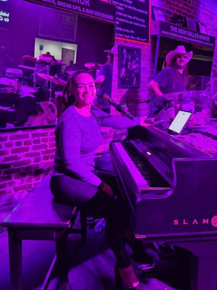 Dueling piano performer entertaining the crowd under purple stage lighting